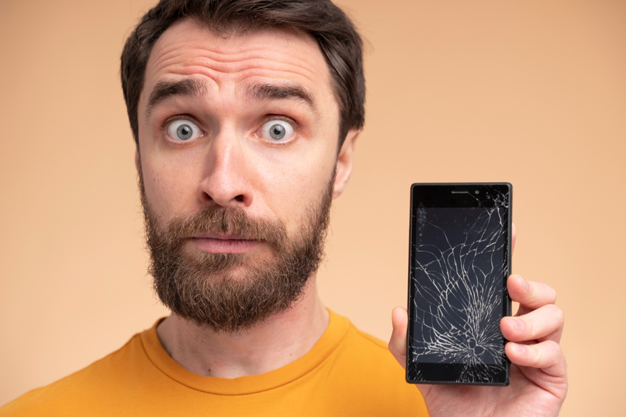 Center portrait shocked young man showing his broken smartphone