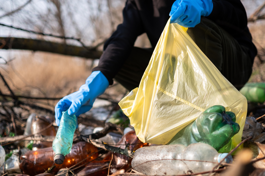 Center man collecting scattered plastic bottles from the ground 1 