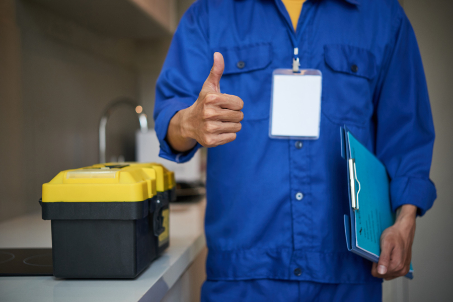 Center unrecognizable male plumber standing near kitchen sink showing thumb up 1 